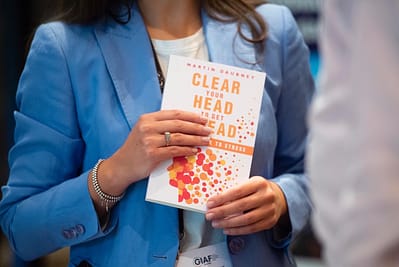 Woman holding "Clear Your Head to Get Ahead: The Antidote to Stress" Book